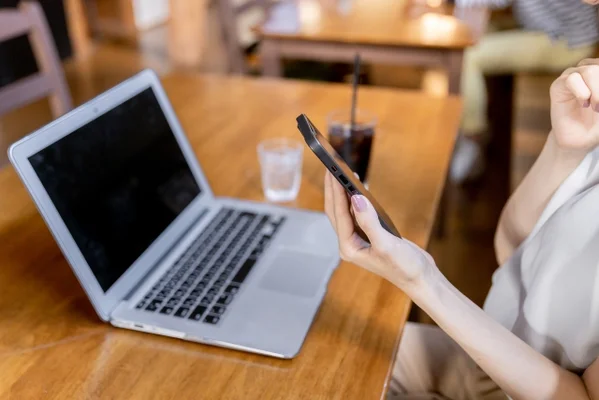 スマホを持ちながらパソコンに向かう人